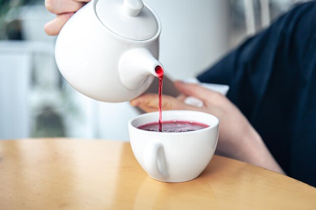 Closeup of a young woman pours tea from a teapot