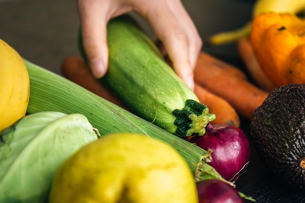 Closeup zucchini in female hands among vegetables on the kitchen table