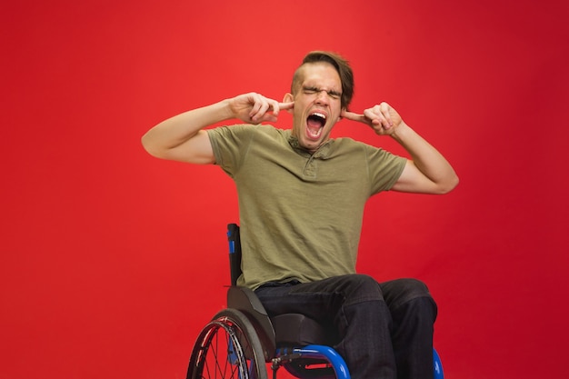 Free photo closing ears. caucasian young disabled man's portrait on red