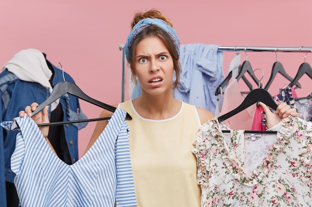 Free photo clothing, fashion, style and people concept. stressed young european woman having indecisive and frustrated look while choosing dress to wear on party but can't find anything suitbale for her