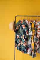 Free photo clothing rack with hawaiian shirts with floral print on hangers and hat