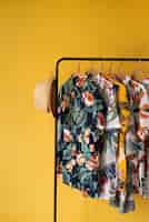 Бесплатное фото Вешалка для одежды с гавайскими рубашками с цветочным принтом на вешалках и шляпе
