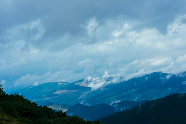 Clouds over the mountain covered with green trees