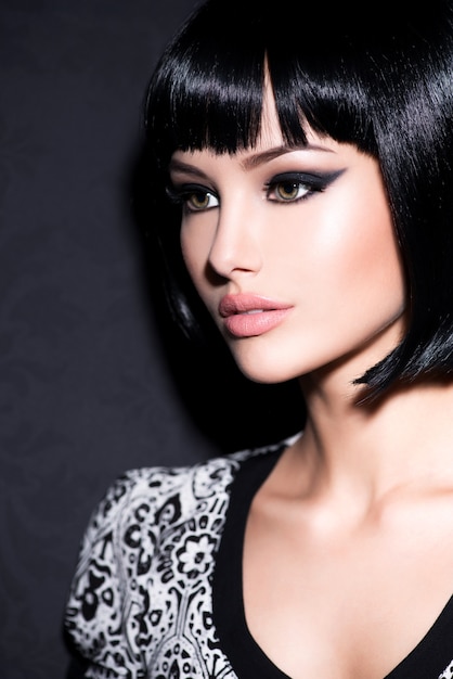 Clouseup портрет красивой женщины с ярким гламурным макияжем и короткими черными прямыми волосами, позирующими