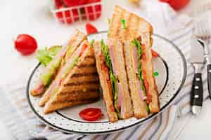 Бесплатное фото Клубный сэндвич - панини с ветчиной, сыром, помидорами и зеленью.