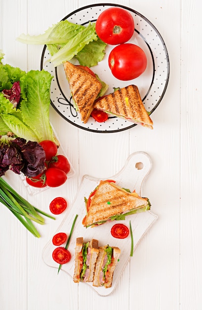 Клубный сэндвич - панини с ветчиной, сыром, помидорами и зеленью. Вид сверху