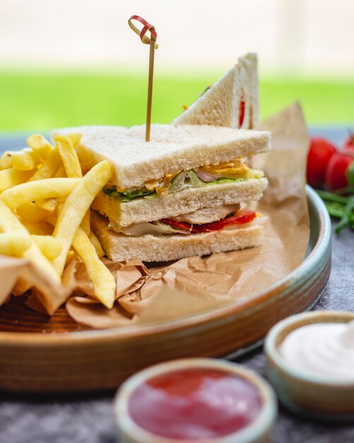 Club sandwich served with french fries mayonnaise and ketchup