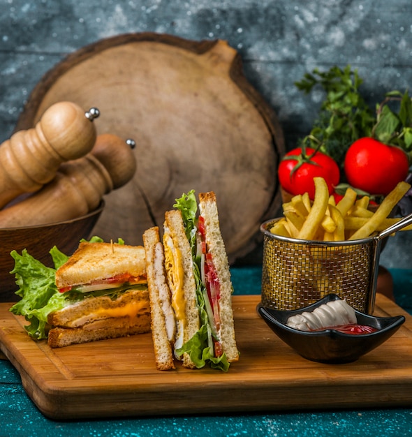 club sandwich served with fries, mayonnaise and ketchup on wood serving board