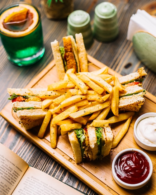 Foto gratuita vista laterale del ketchup della maionese delle patate fritte del cetriolo del pomodoro del pollo del pane tostato del panino di club