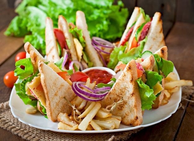 Club sandwich con formaggio, cetriolo, pomodoro, carne affumicata e salame. servito con patatine fritte.