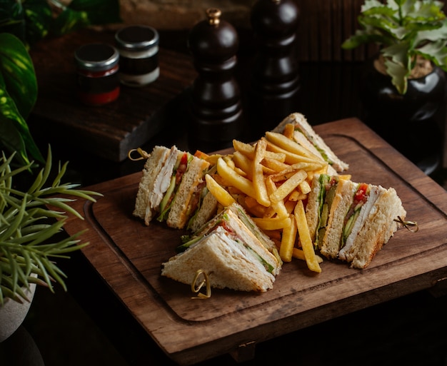 Клубные бутерброды на четыре персоны с картофелем фри на ресторане с листьями розмарина