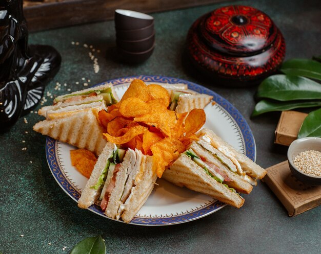 Club sandwiches and potato chips in a plate.