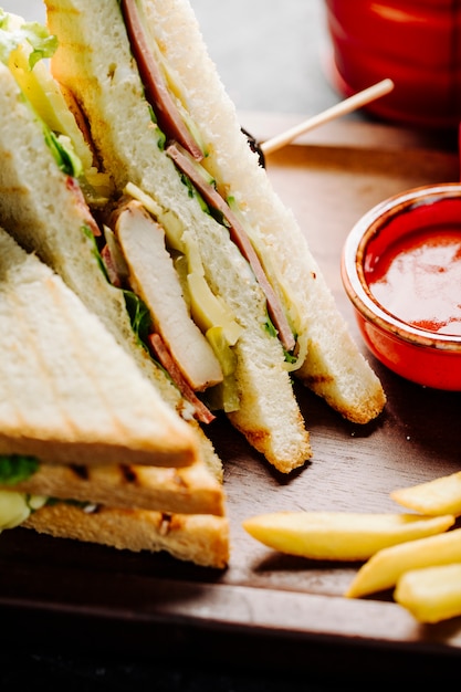Club sandwiches with potatoes and red sauce.