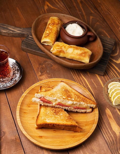 サラミ、ベーコン、ブリチクのクラブサンドイッチ、ヨーグルトと紅茶の木の板
