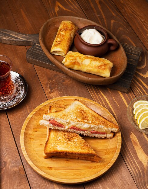 サラミ、ベーコン、ブリチクのクラブサンドイッチ、ヨーグルトと紅茶の木の板