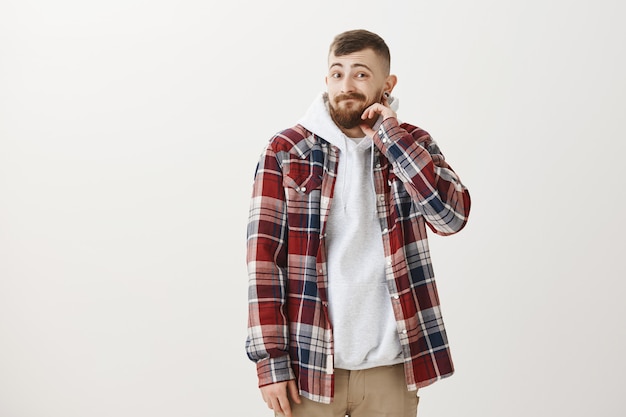 Clueless awkward hipster guy scratching beard and looking guilty