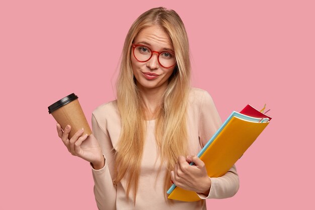 clueless blonde college student posing against the pink wall