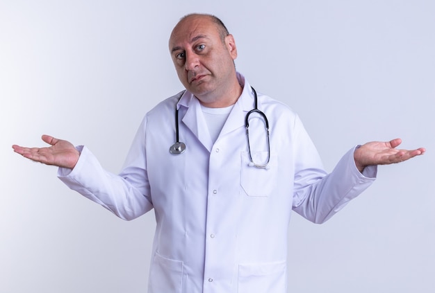 Невежественный мужчина-врач средних лет в медицинском халате и стетоскоп, смотрящий в камеру, делает жест, изолированные на белом фоне