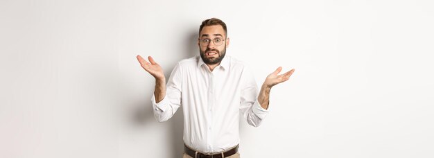 Clueless worried manager shrugging looking confused standing over white background