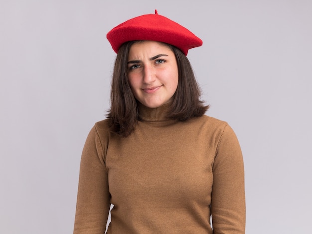 Clueless young pretty caucasian girl with beret hat  isolated on white wall with copy space