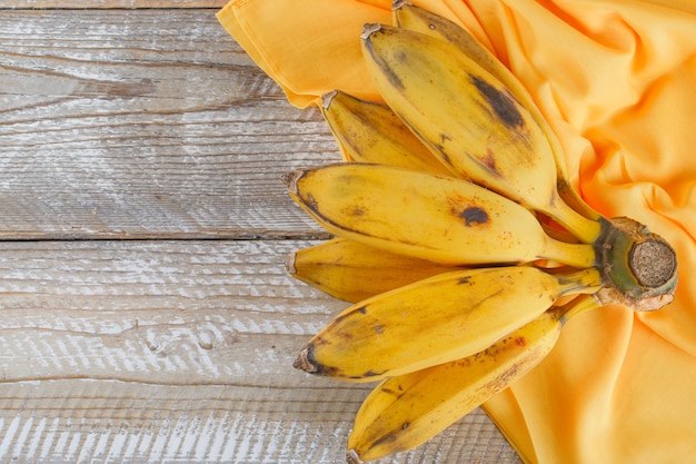 Cluster of bananas flat lay on wooden and textile