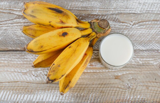 Cluster of bananas with milk flat lay on a wooden