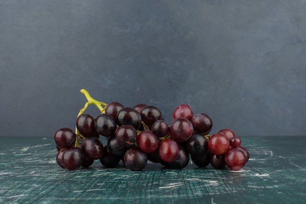 A cluster of black grapes on marble table.
