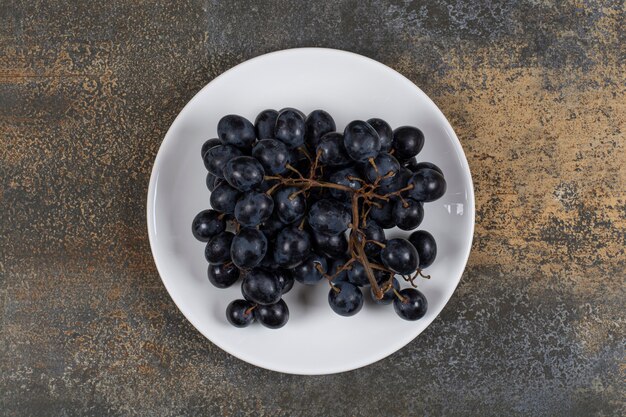 Cluster of black grapes on white plate.