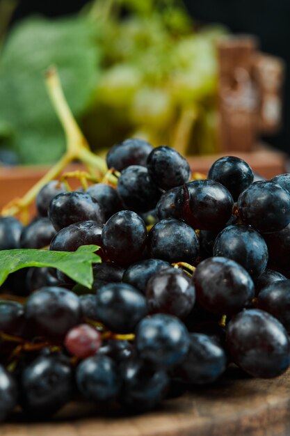 A cluster of black grapes on wooden plate, close up. High quality photo