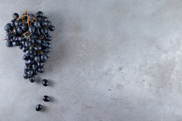 Cluster of fresh black grapes placed on stone background. 