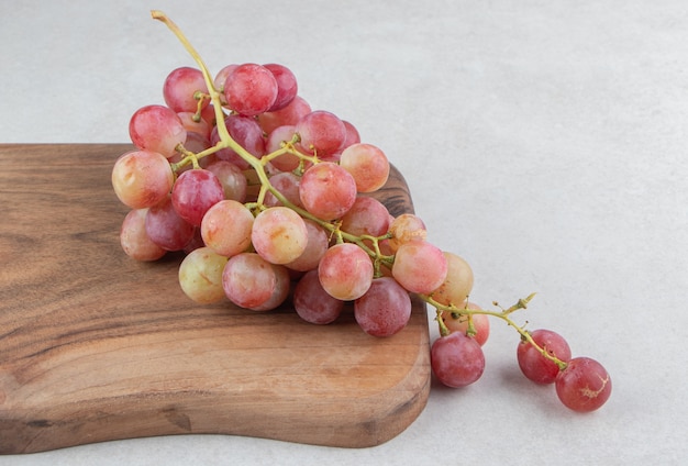 Cluster of fresh grapes on wooden board.