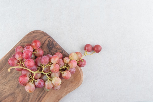 Гроздь свежего винограда на деревянной доске.