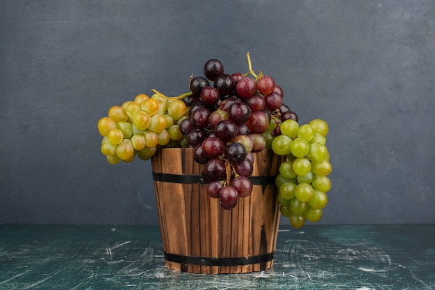 Гроздь зеленого и черного винограда на мраморном столе.