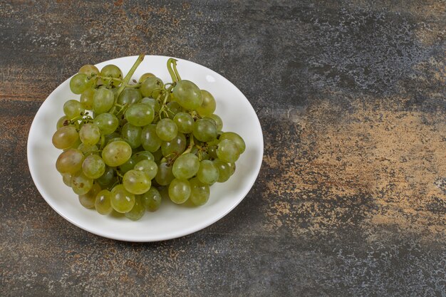 Cluster of green grapes on white plate. 