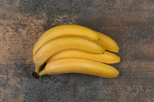 Cluster of ripe bananas on marble surface