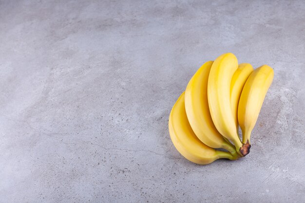 Cluster of ripe yellow bananas placed on stone background. 