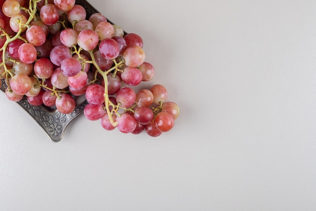 Clusters of grape and an ornate tray on marble 