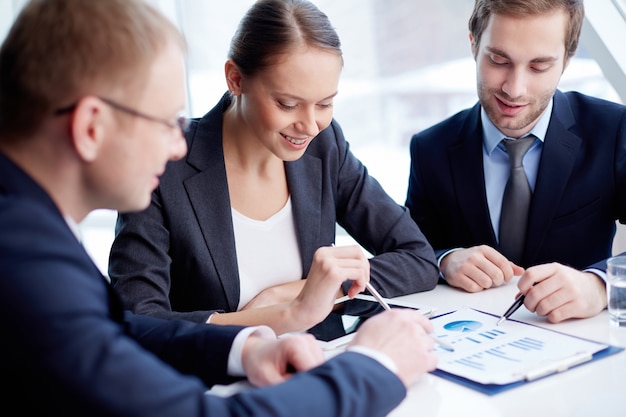 Co-workers with pens pointing a bar chart