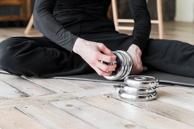 Free photo coach sitting on floor and preparing dumbbell