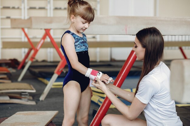 学生とコーチ。女の子の体操選手は、さまざまな体操やジャンプを行います。子供とスポーツ、健康的なライフスタイル。