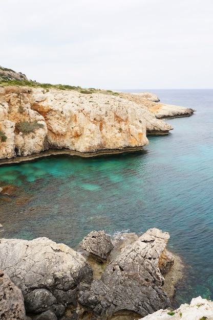 Free photo the coastline with rocky mountains and calm water under the blue sky