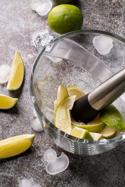 Cocktail being made in pitcher with lime slices and ice cubes