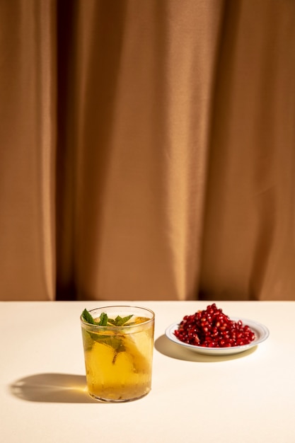 Cocktail drink with pomegranate seeds on white table