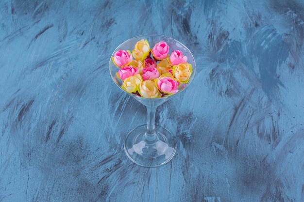 Cocktail glass with colorful flower arrangement on blue.