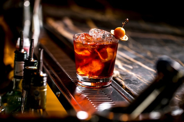 A cocktail glass with ice cubes garnished with dried lemon and fruit