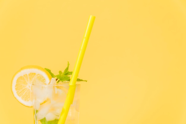 Free photo cocktail glass with straw and lemon on yellow background