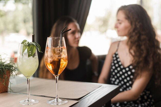 Cocktail glasses in front of two female friends