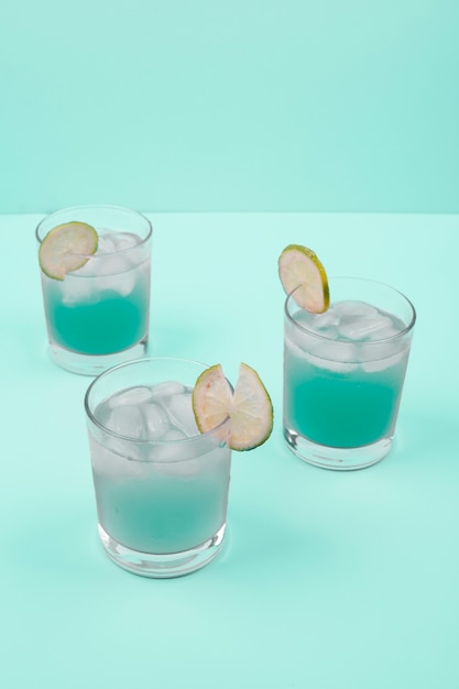 Cocktail glasses with ice cubes and lemon slice on mint background