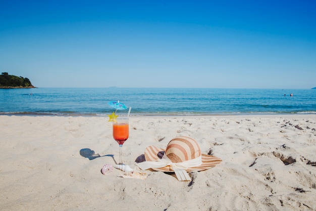 Free photo cocktail and hat on beach