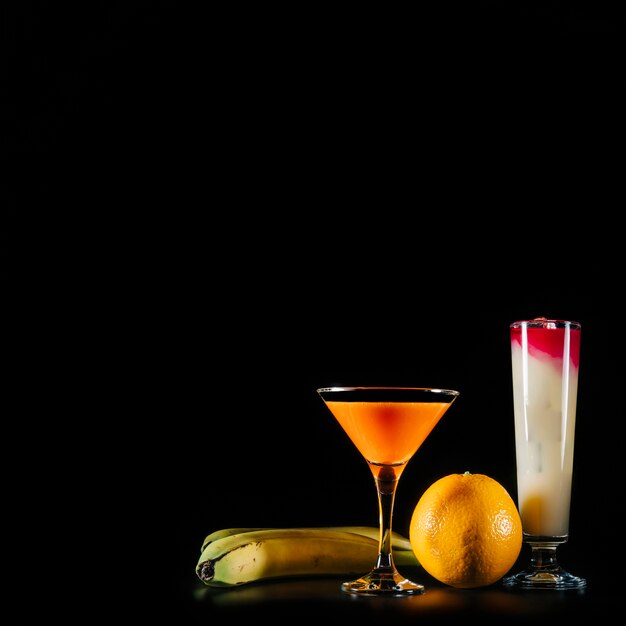 Cocktail and tropical fruits on black background